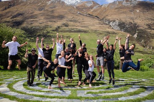 A group of people all jumping in the air on top of a stone labyrinth