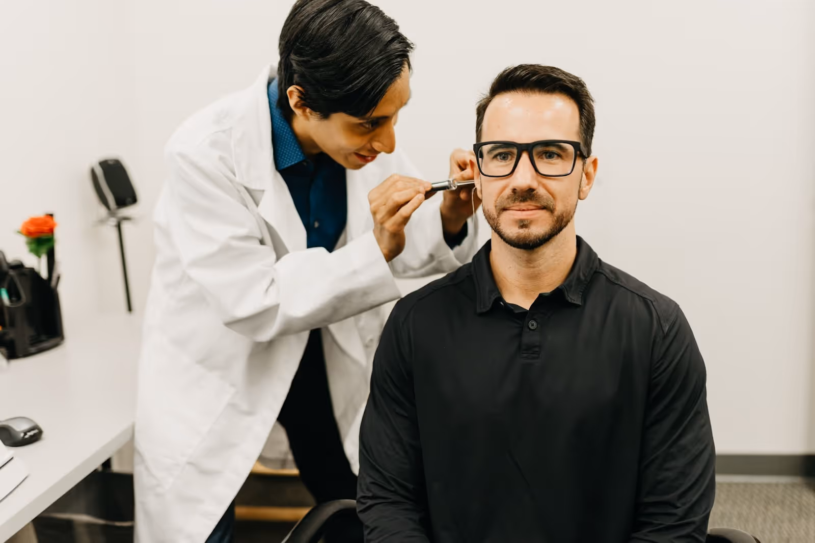Audiologist examining a male patient’s ear during a hearing check-up in a clinic, highlighting the importance of regular hearing screenings.