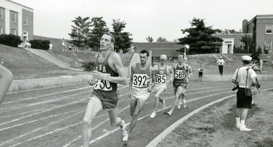 A black-and-white image from the 1965 Deaflympics shows four track athletes mid-race on an outdoor track, representing various countries including the USA.