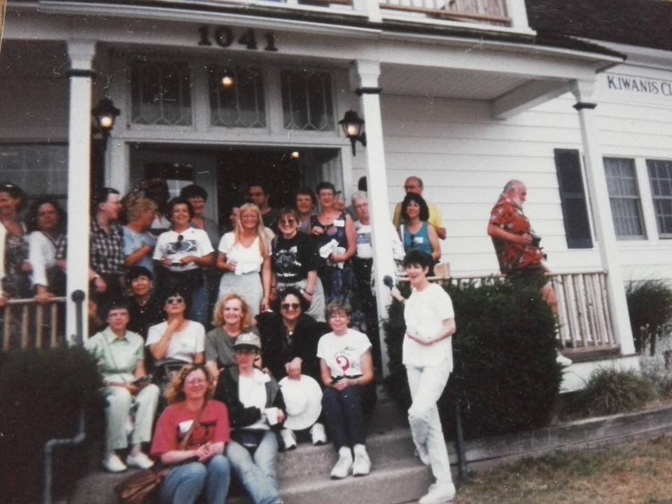 A vintage photo of SayWhatClub members at the 1999 Cape May convention, smiling together on the steps of a white building.
