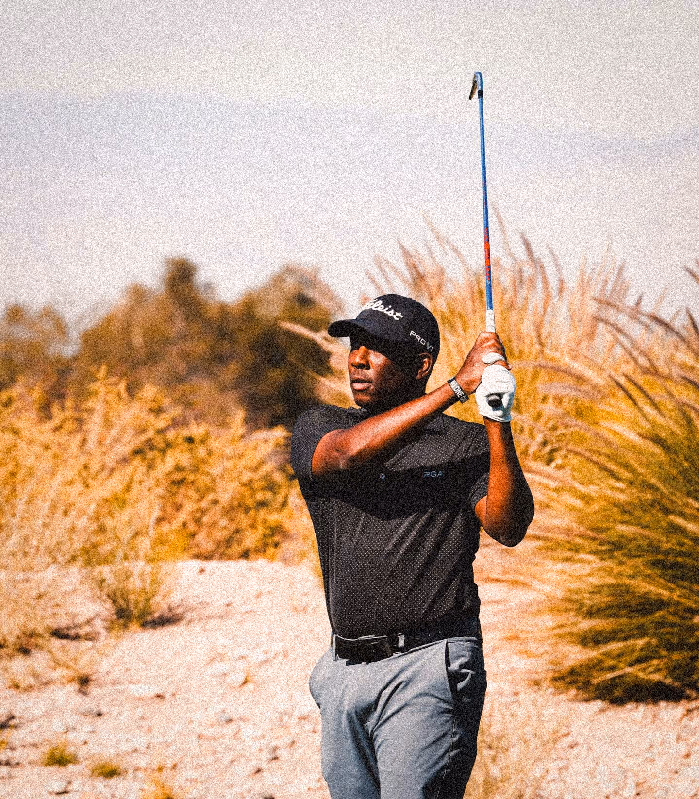 Kevin Hall follows through on a drive, framed by sunlit brush and clear skies.