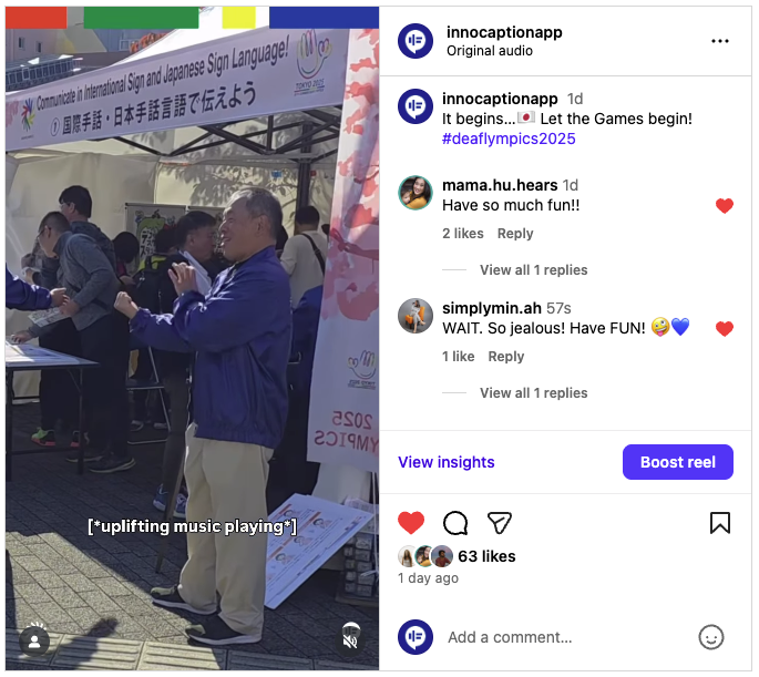 A man signs in front of a booth promoting International Sign and Japanese Sign Language at the Deaflympics. People gather behind him, and the booth displays banners for Deaflympics 2025. Bright sunlight fills the outdoor event space.