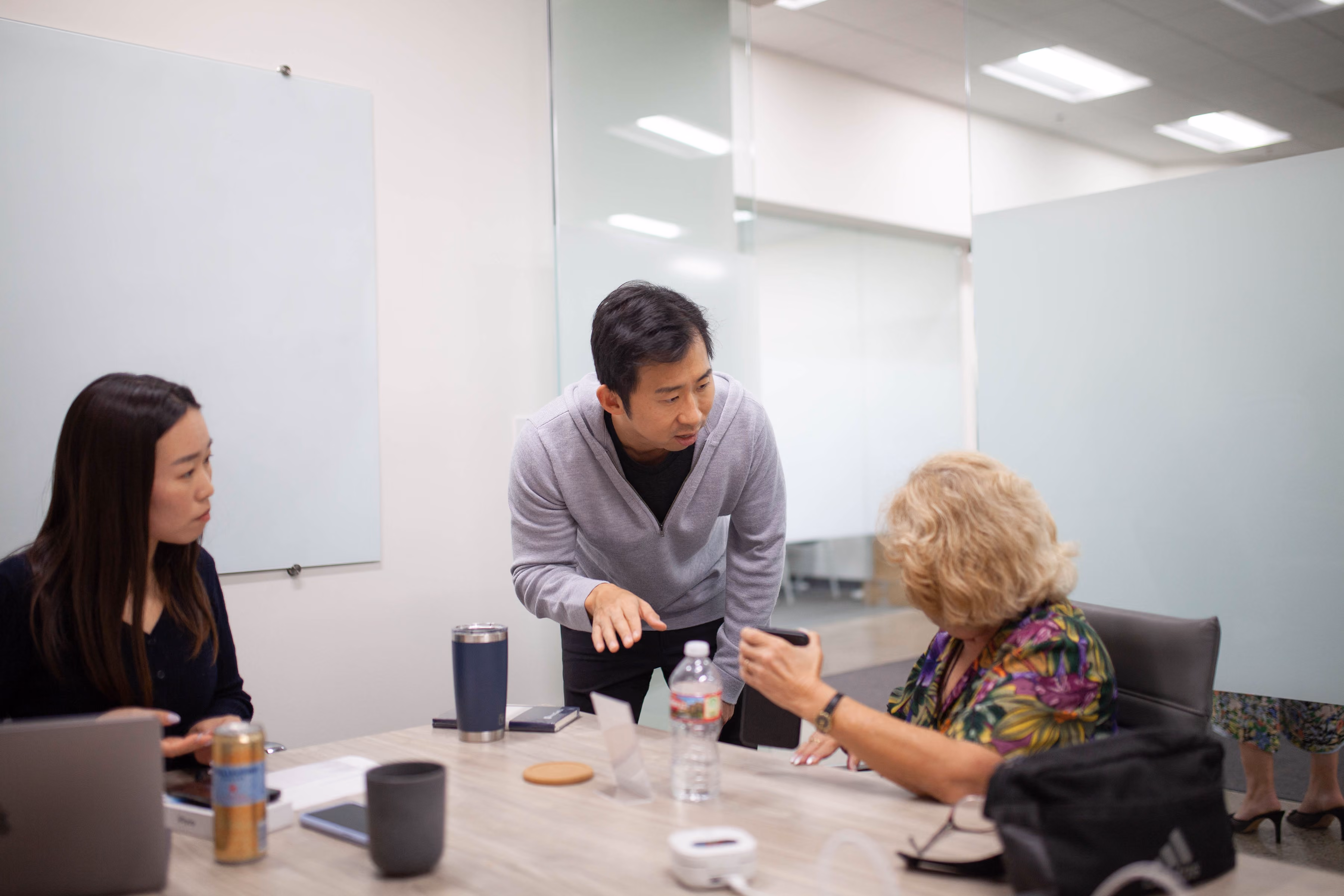 An InnoCaption team member works with a user to troubleshoot a Bluetooth audio issue on her smartphone while another team member looks on.