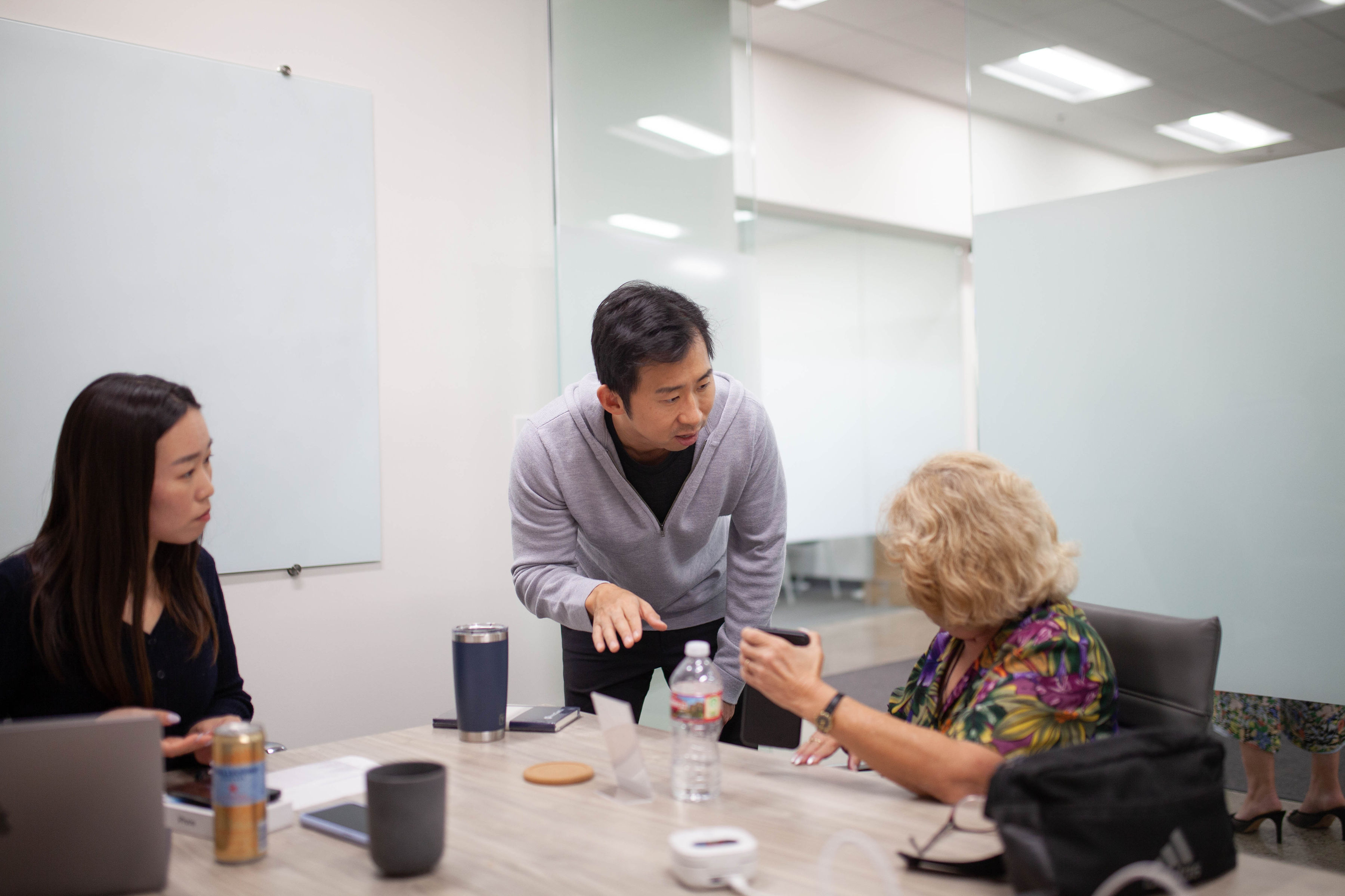 An InnoCaption team member works with a user to troubleshoot a Bluetooth audio issue on her smartphone while another team member looks on.