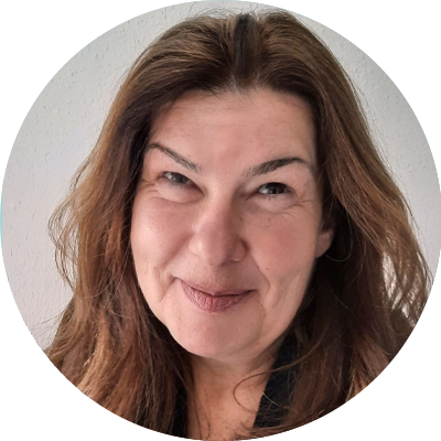 Porträt einer lächelnden Frau mit langen braunen Haaren vor weißer Wand.