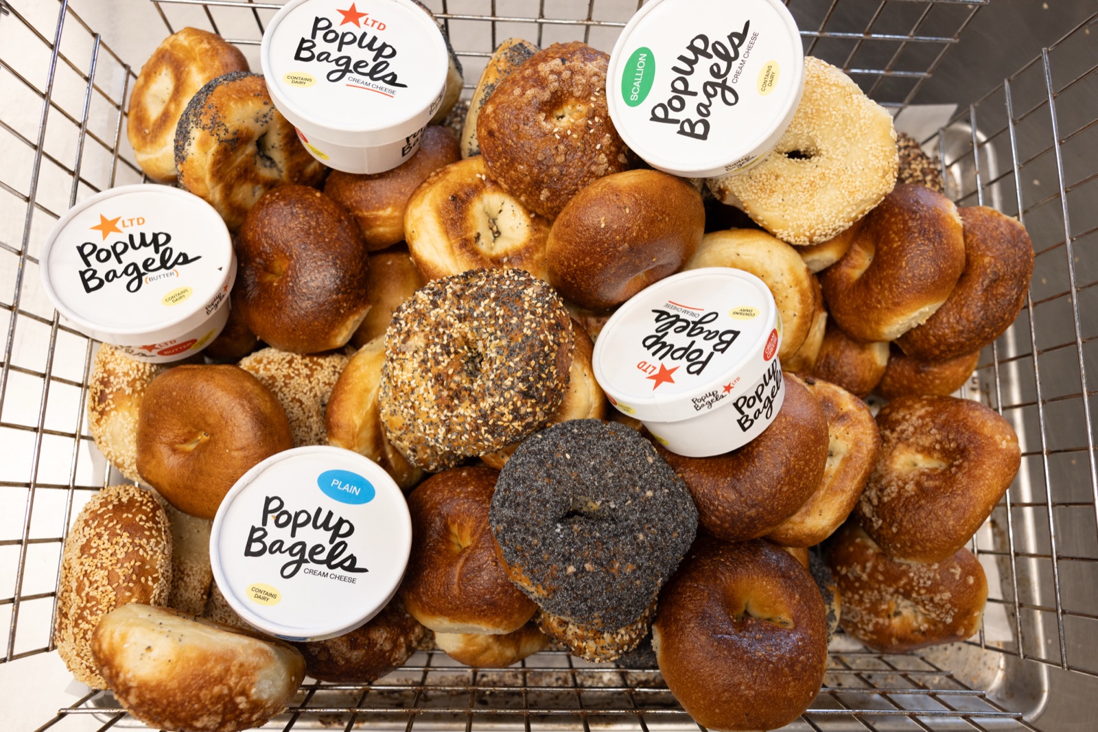 PopUp Bagels and cream cheese tubs in a wire basket
