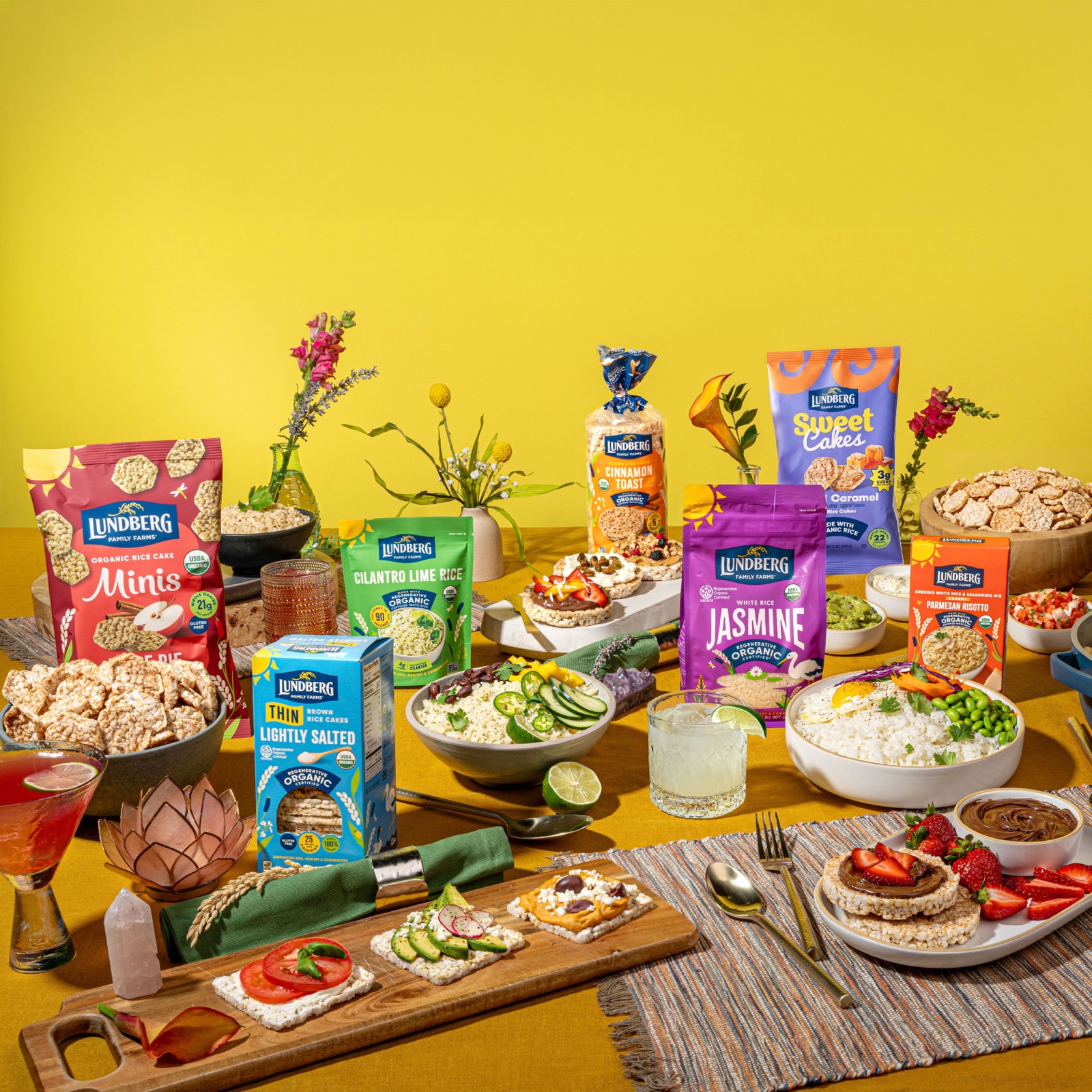 A spread of Lundberg Family Farms rice and rice cake products styled on a table against a yellow background