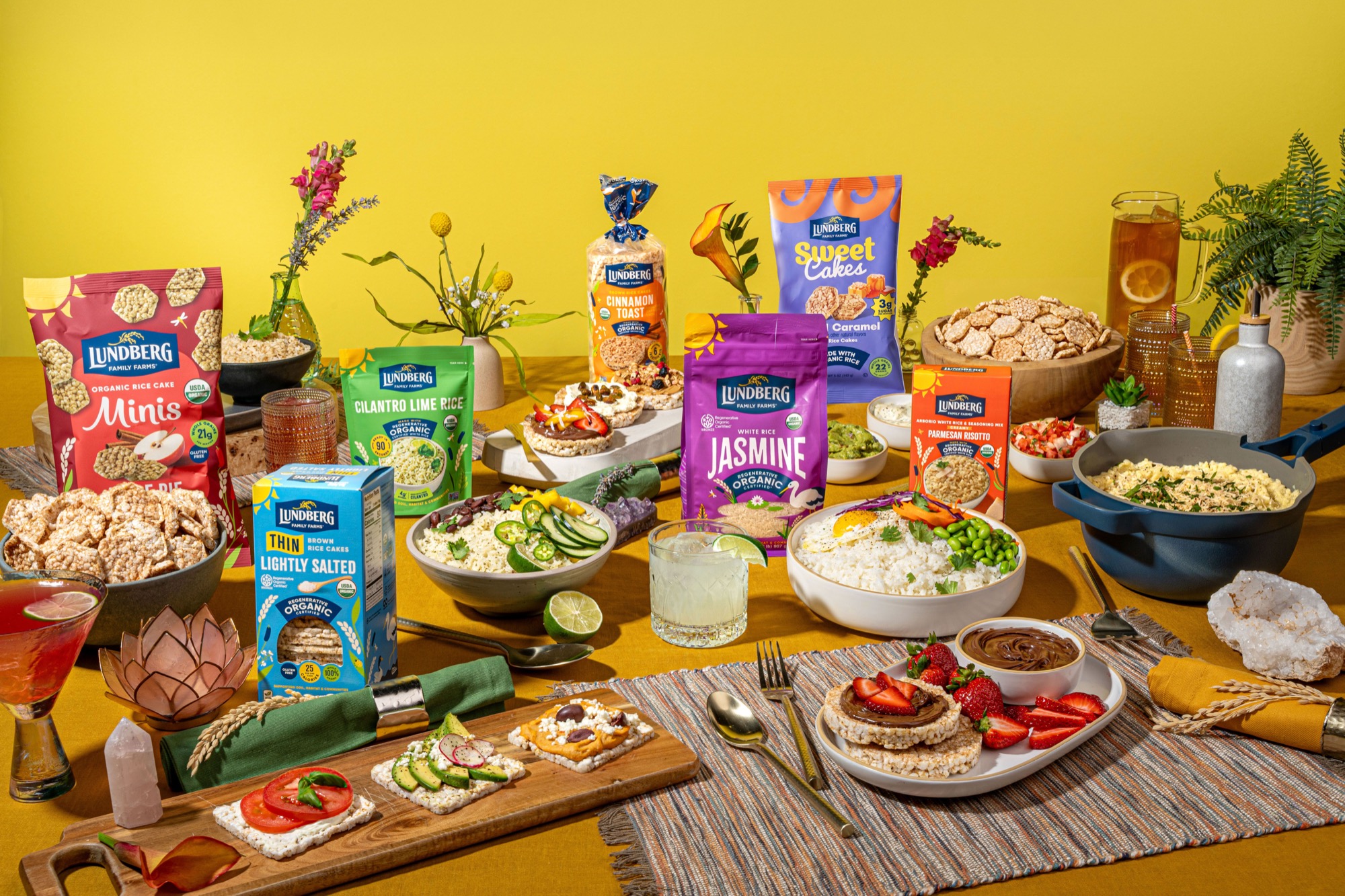 A spread of Lundberg Family Farms rice and rice cake products styled on a table against a yellow background