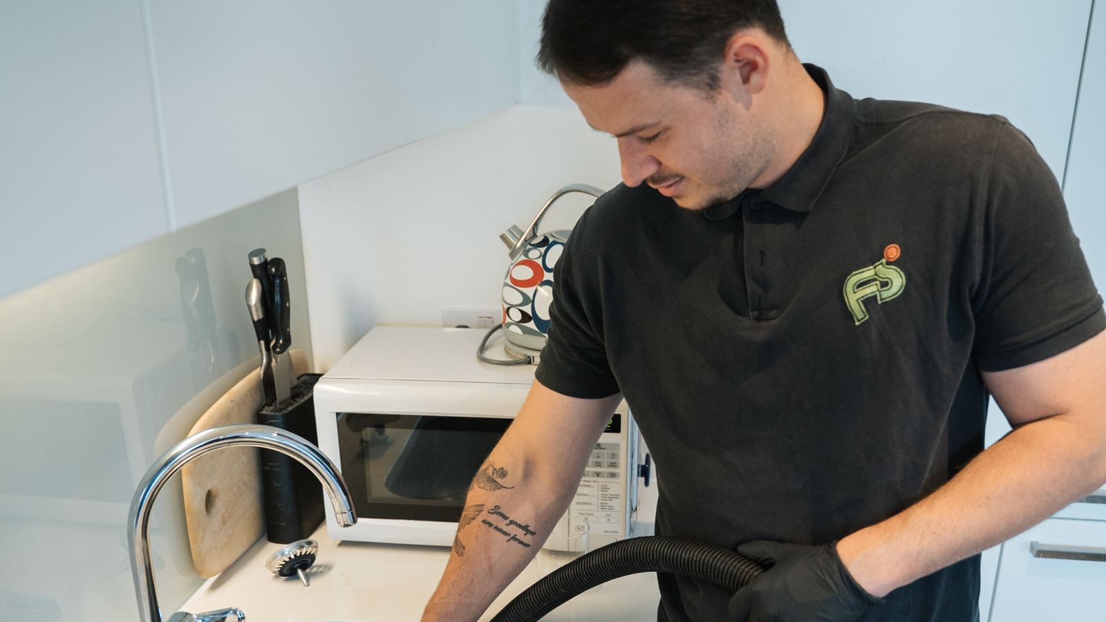 FS Group engineer clearing a blocked kitchen sink with a drain hose
