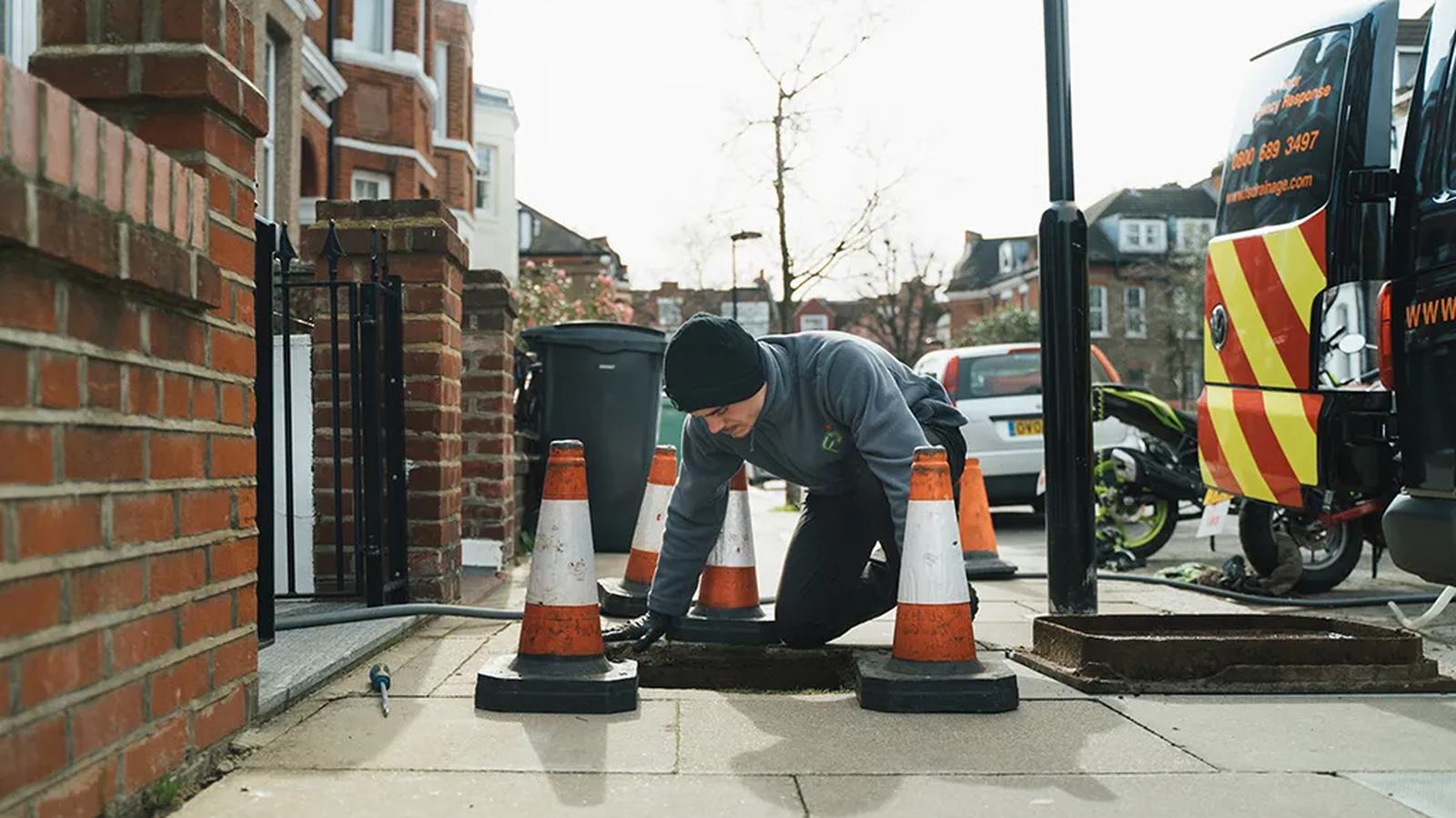 FS Group engineer lifting a drain cover on a residential street