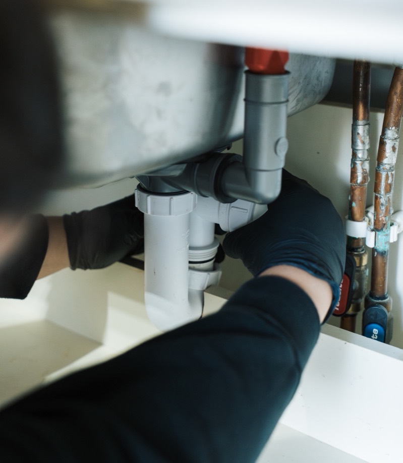 FS Group engineer working on the shared waste pipework under a sink