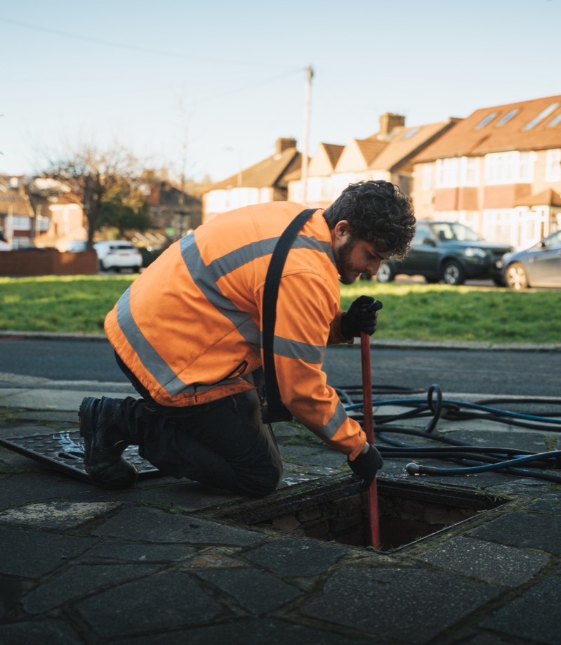 FS Group engineer rodding an open manhole on a residential street