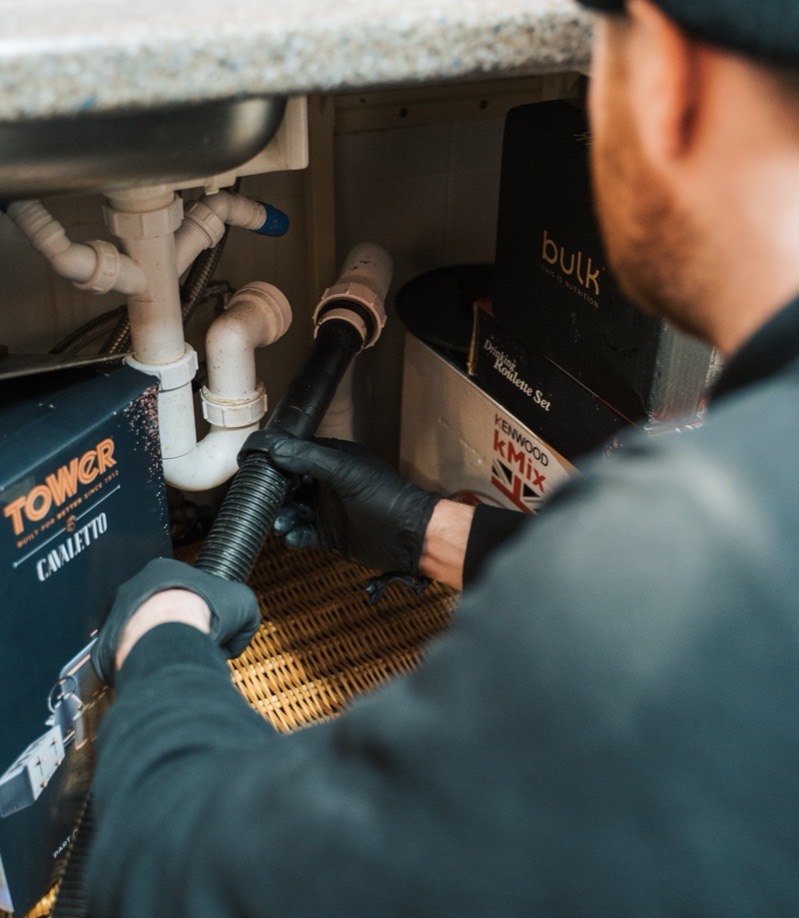 FS Group engineer inspecting the waste pipework under a sink