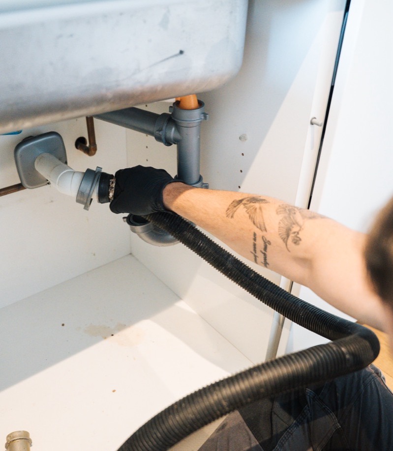 FS Group engineer feeding a camera hose into the waste under a sink