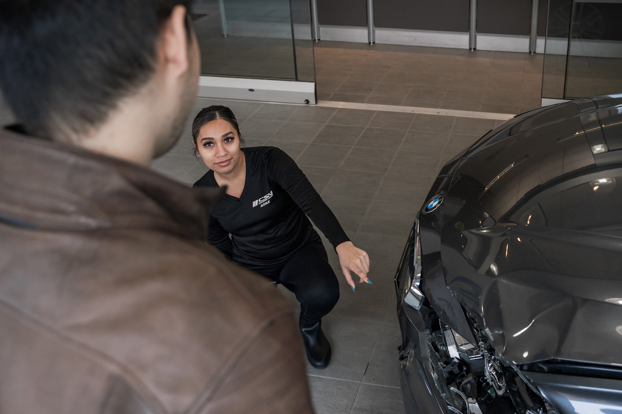 A CSN Avenue Collision advisor points out front-end damage on a grey BMW while walking the owner through an estimate