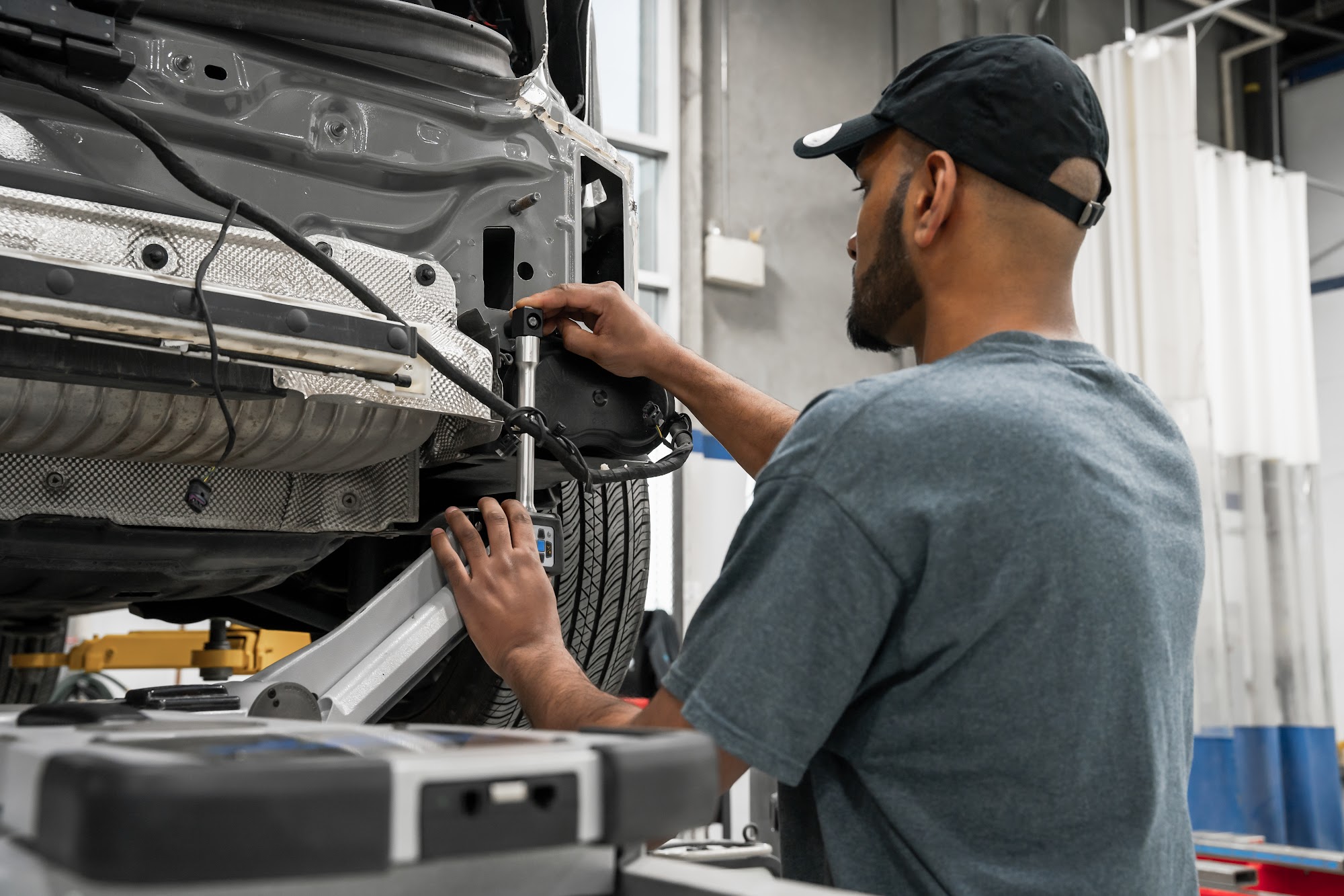 A CSN Avenue Collision technician works on the rear structure of a car raised on a hoist