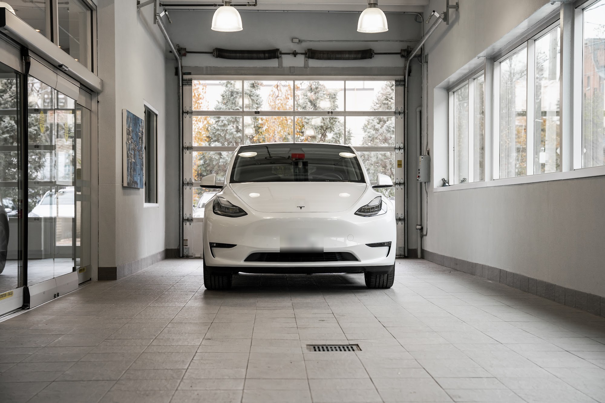 A white Tesla Model Y parked in the intake bay at CSN Avenue Collision on Macpherson Avenue