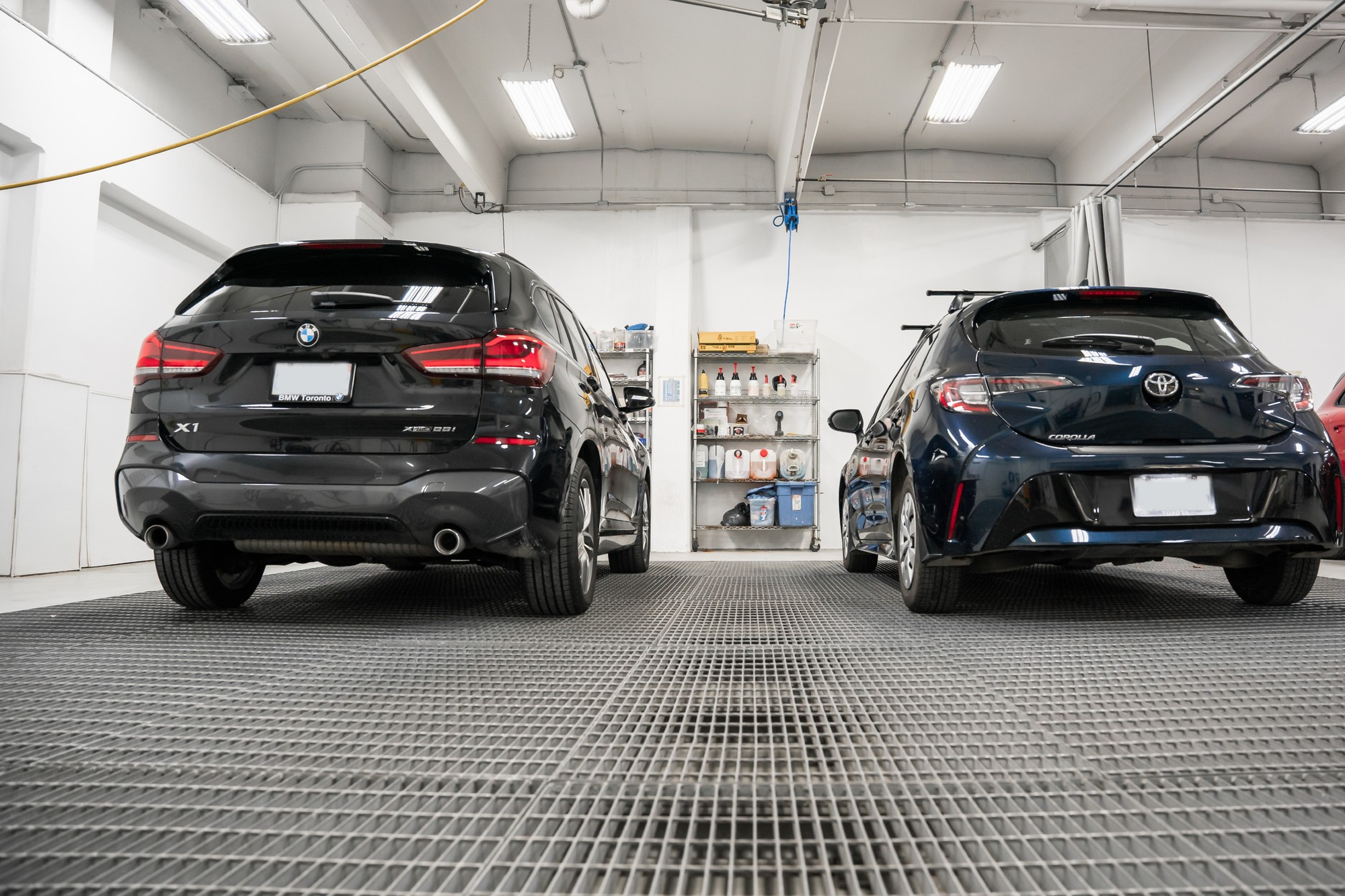 Rear view of a BMW X1 and a Toyota Corolla side by side on the shop floor at CSN Avenue Collision
