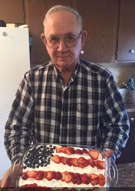 A man holding a cake with strawberries on it