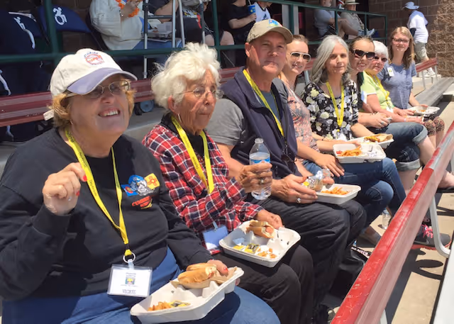 A group of people sitting next to each other at a baseball game