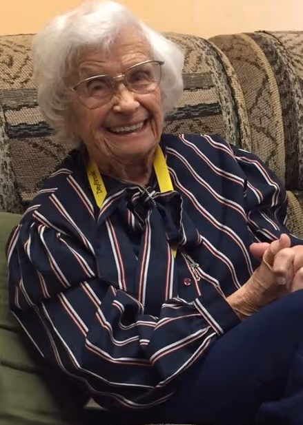 An old woman sitting on a couch smiling