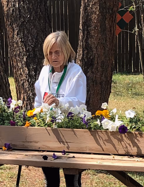A woman sitting on a bench with flowers in it