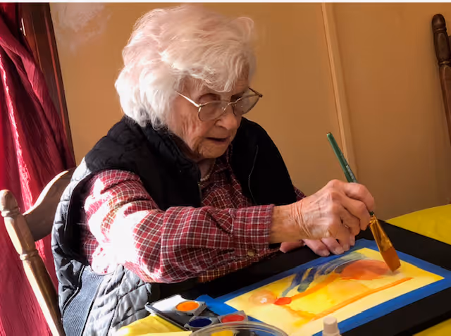 A woman sitting at a table with a painting on it