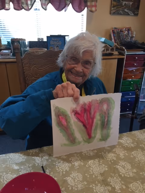 An older woman holding up a piece of art