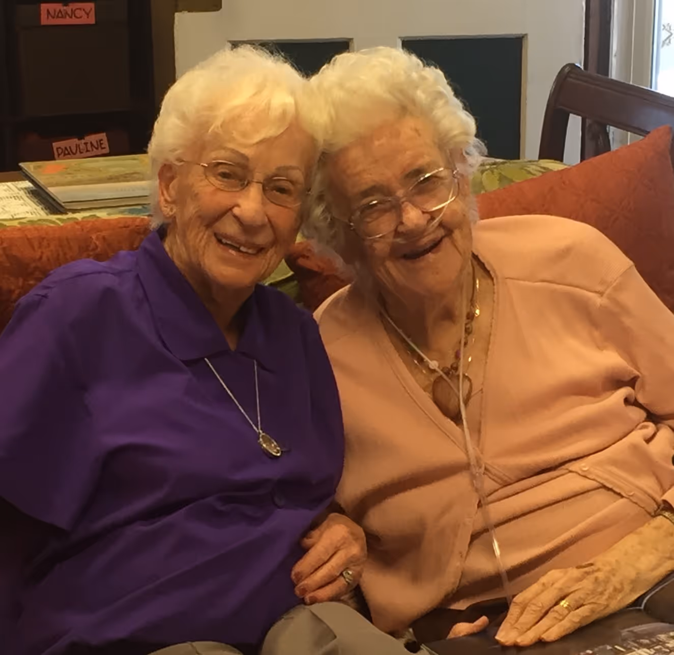 A couple of women sitting next to each other on a couch