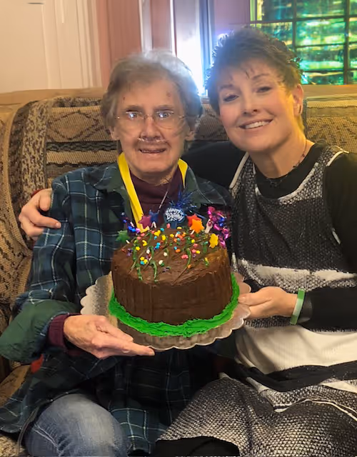 A man and woman sitting on a couch holding a cake