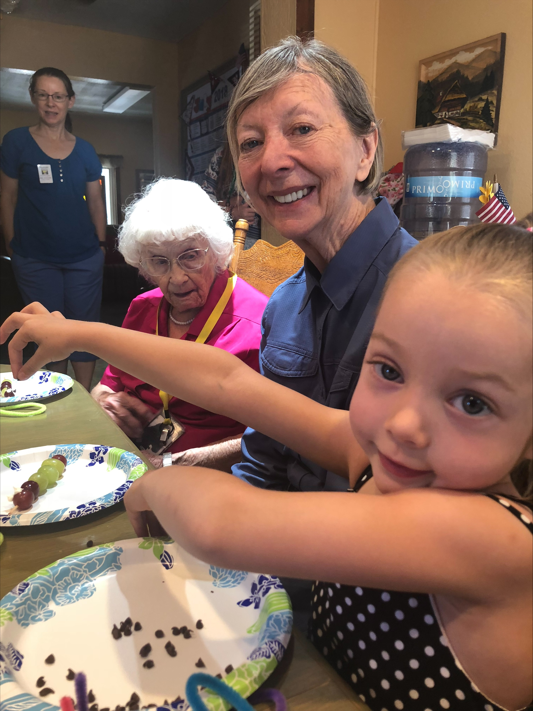 Three generations of women smiling while enjoying a meal together indoors