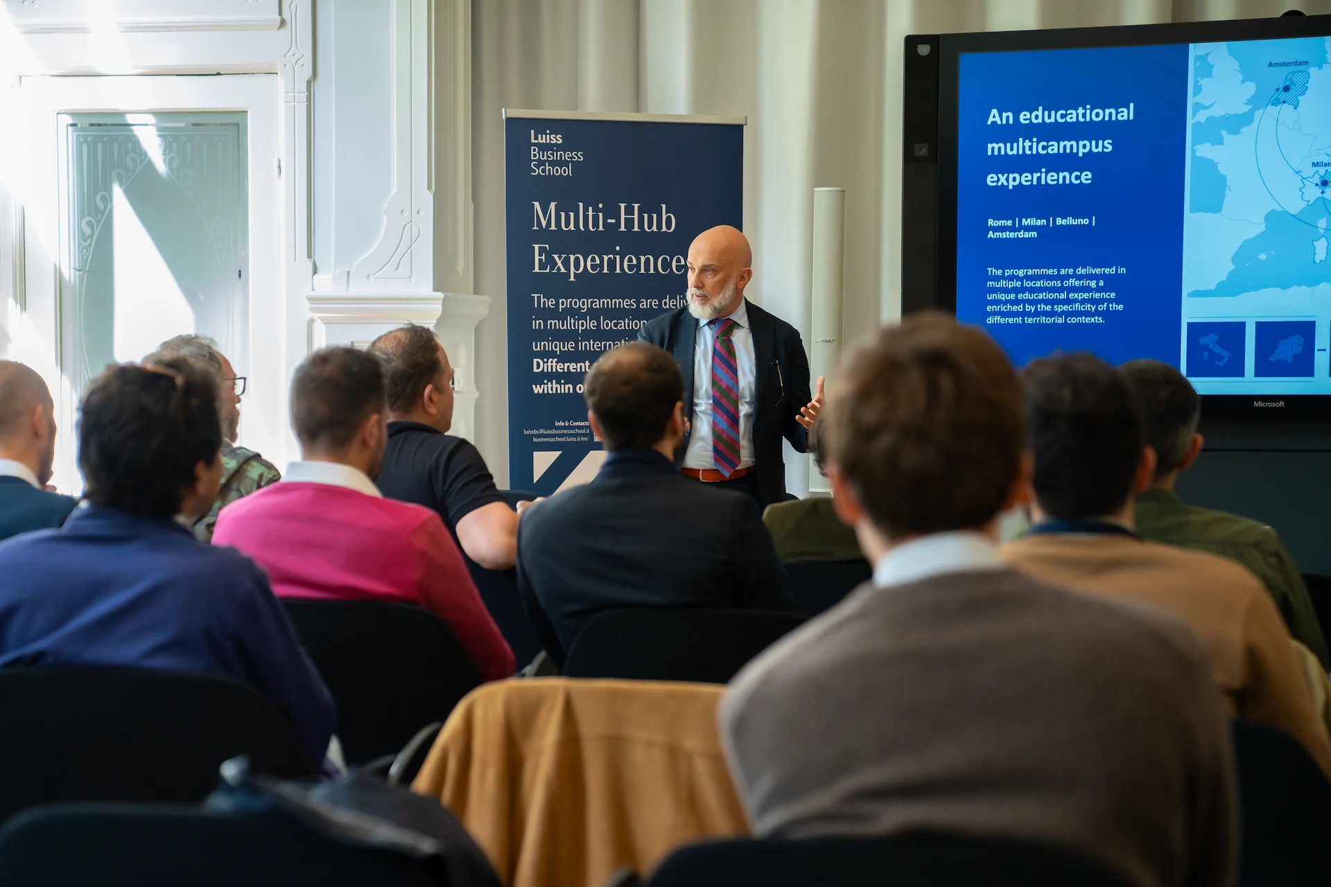 Two young men wearing casual jackets standing on an industrial rooftop with metal structures.