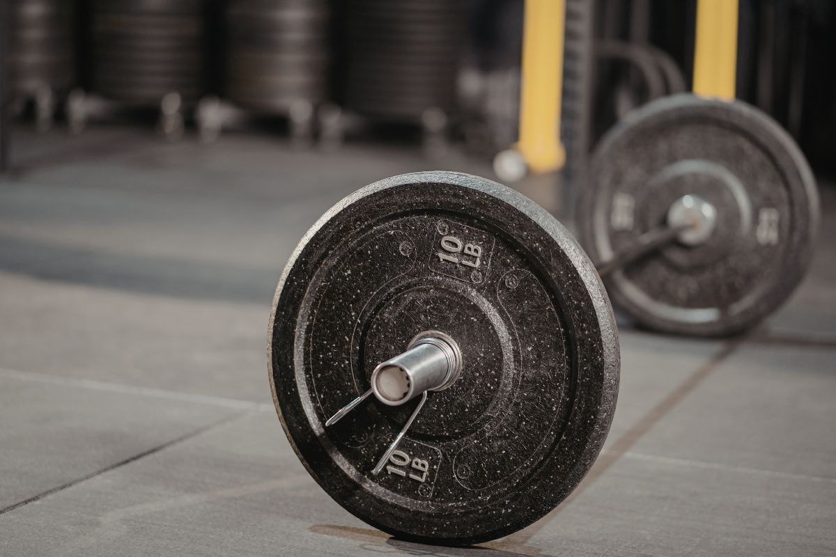 Bilden föreställer en skivstång liggandes på golvet i ett gym