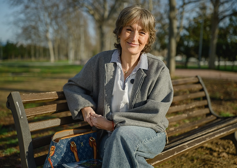 Mujer sonriente en un banco del parque, relajada y segura.