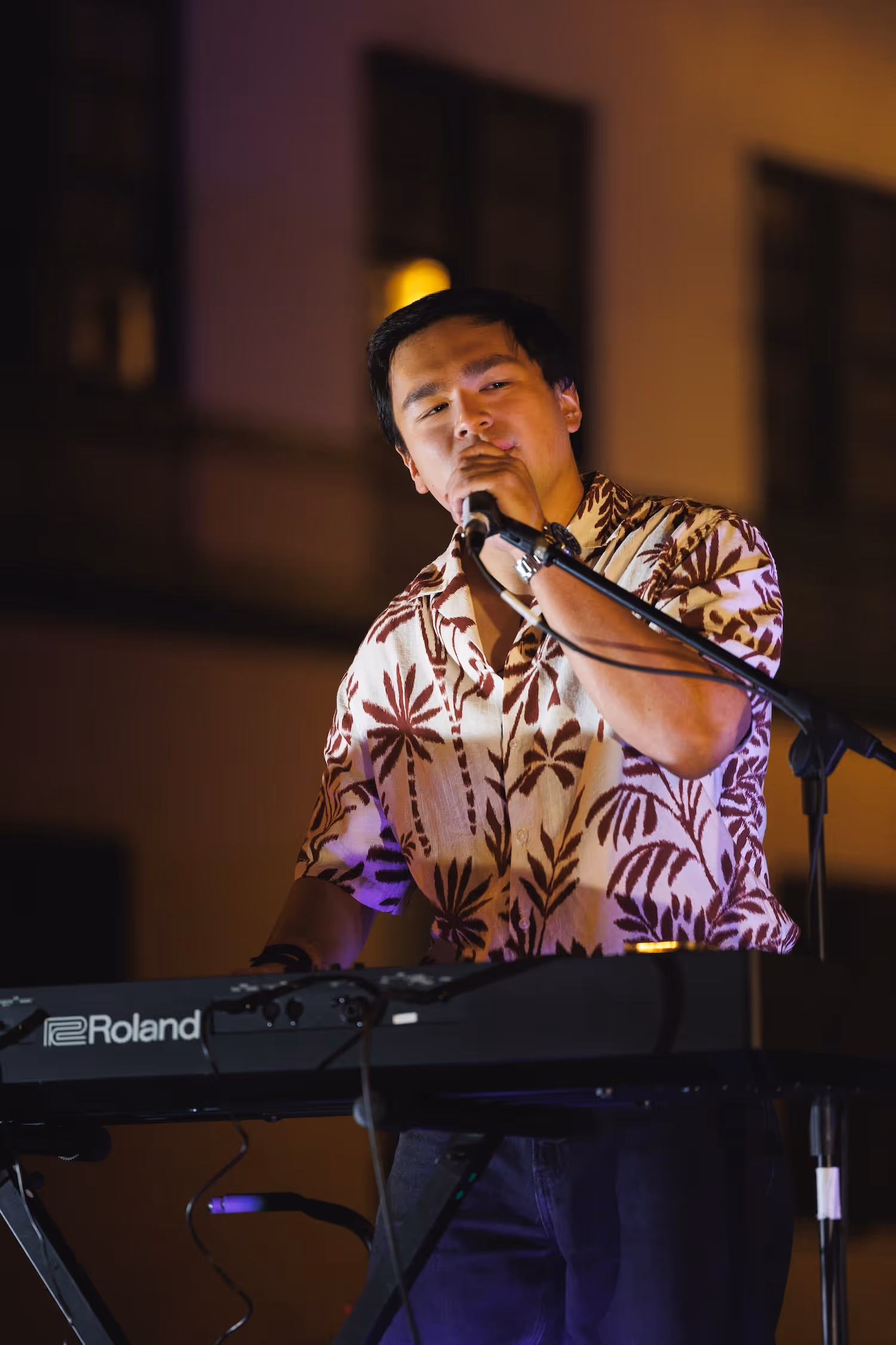 Artist singing and playing keyboard on stage.