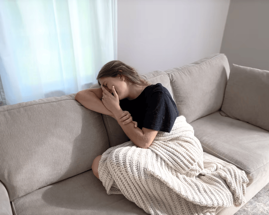 Eine Frau liegt auf dem Sofa, weil das Chronischen Erschöpfungssyndrom (ME/CFS) sie müde macht.