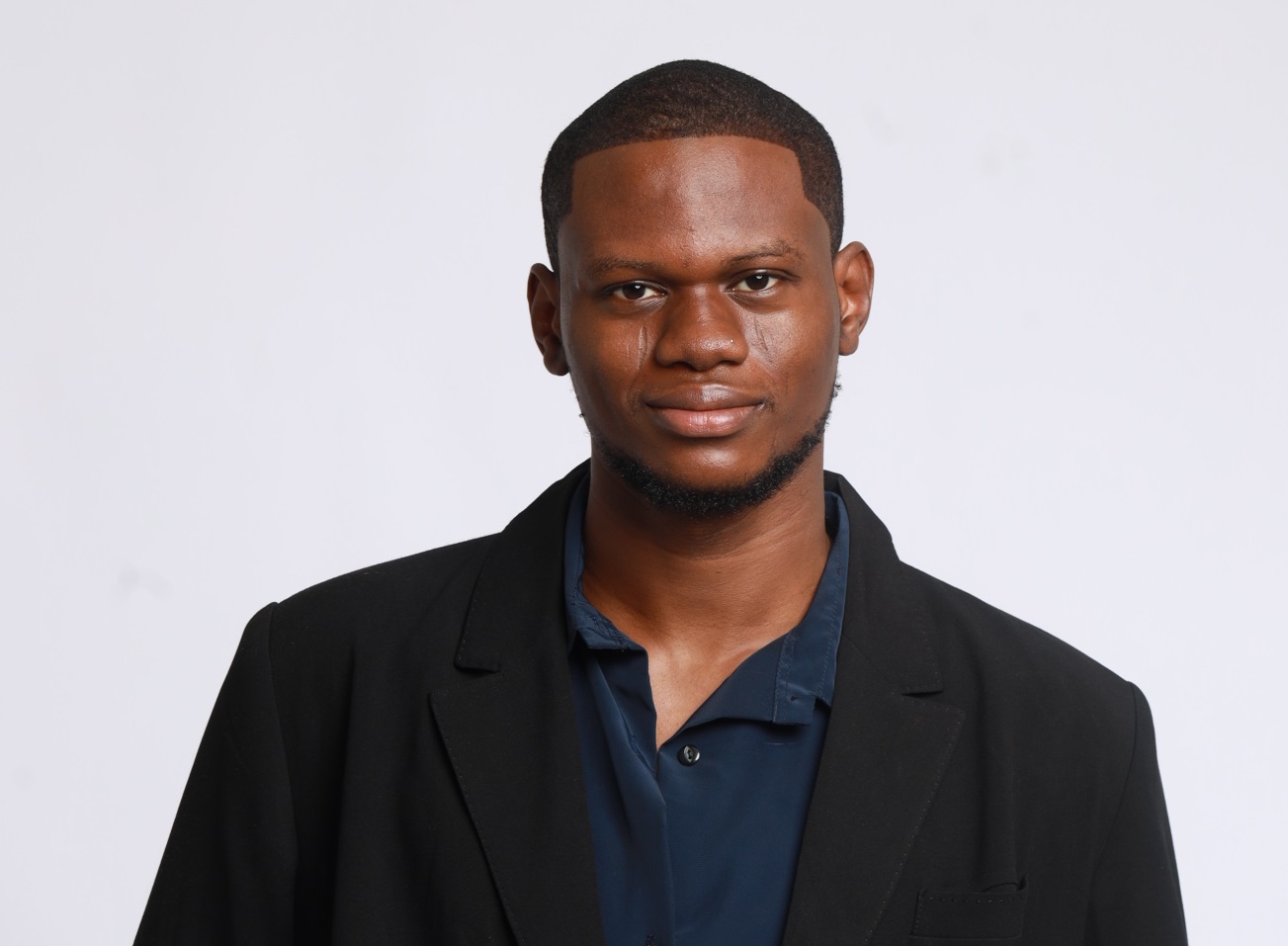 Photo of Bolanji ,  a Nigerian person with short brown hair, wearing a black suit jacket and navy shirt
