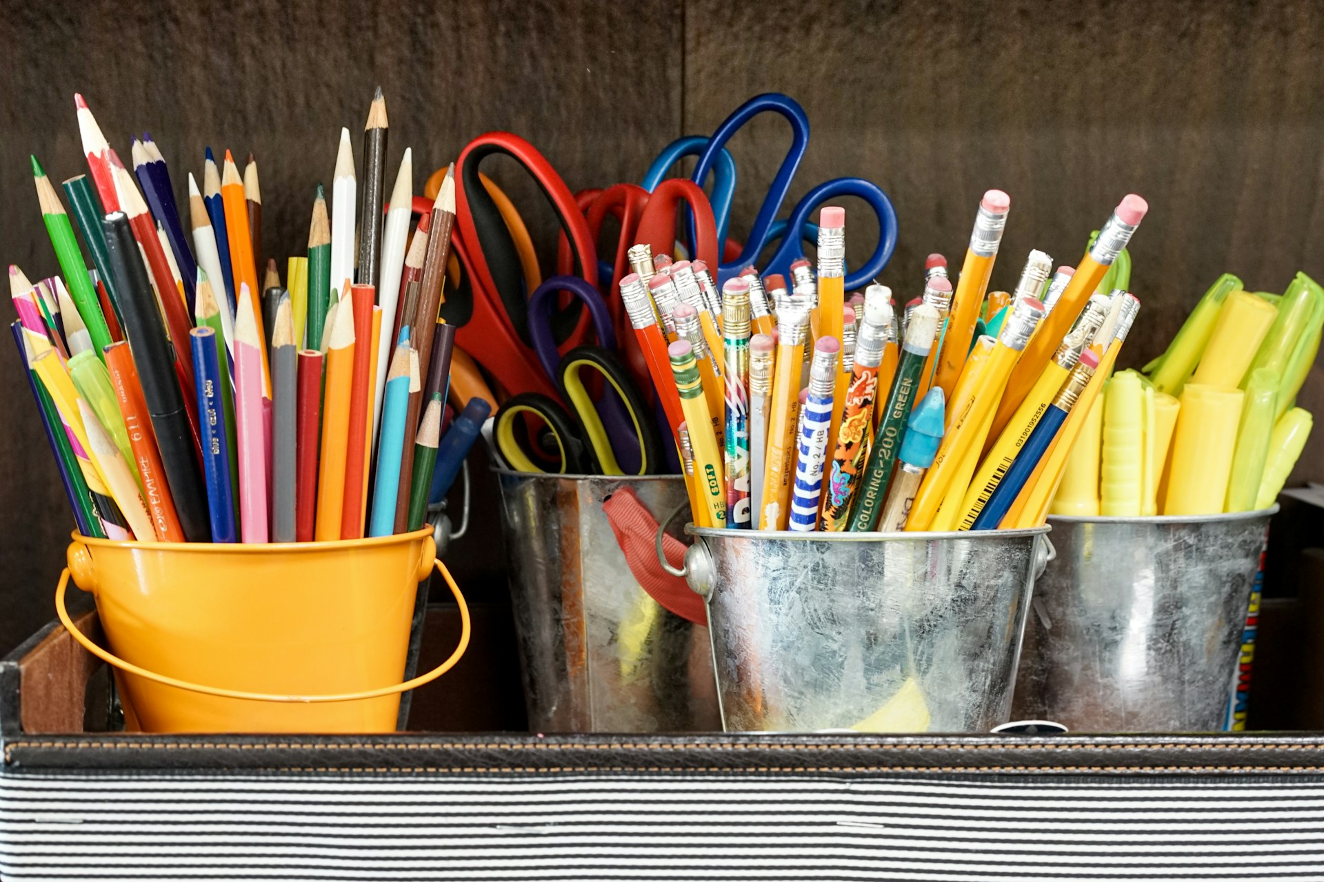 Photo of 4 small buckets one with crayons, one with scissors, one with pencils with chalk in an open drawer - Photo Credit Laura Rivera from Unsplash