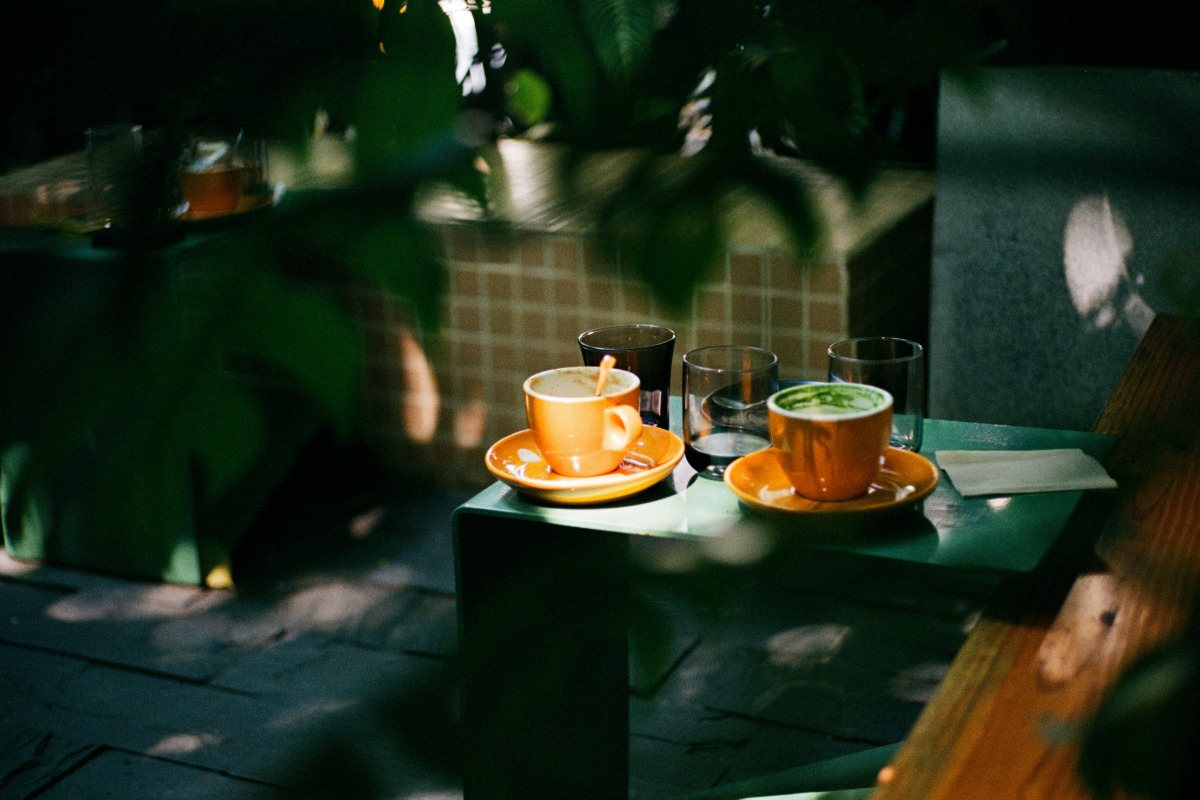 Two cups of coffee on saucers beside drinking glasses on an outdoor table
