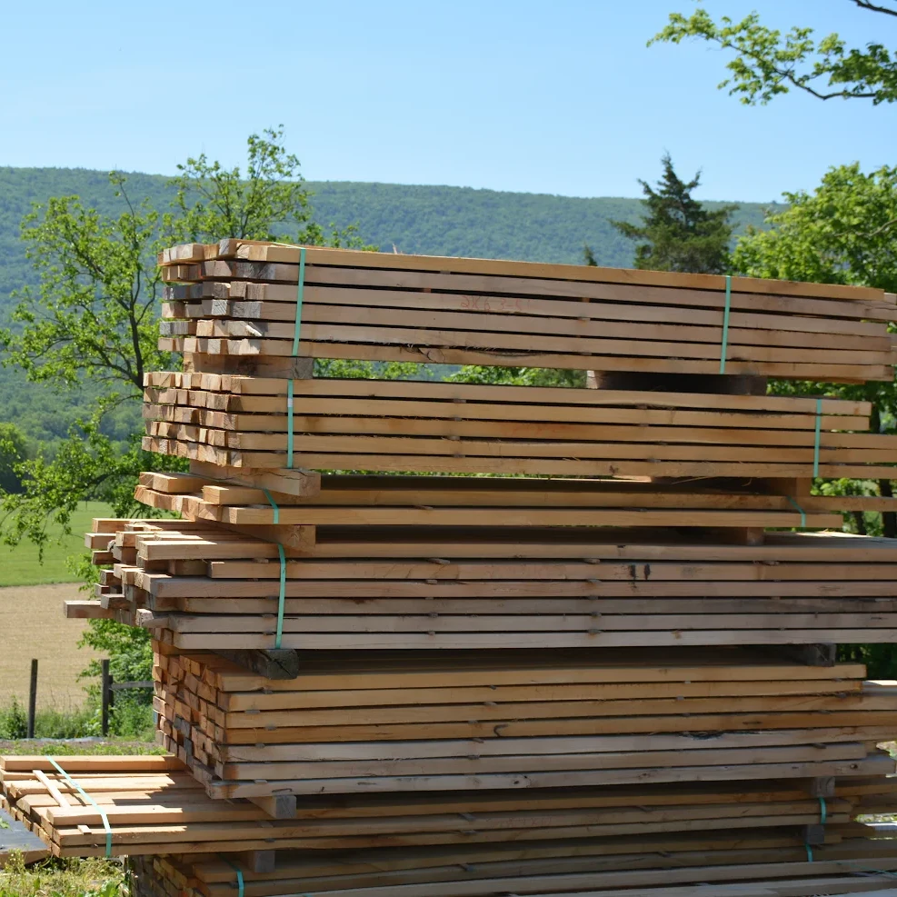 Stacked black locust boards air-drying outdoors with the Appalachian mountains in the background