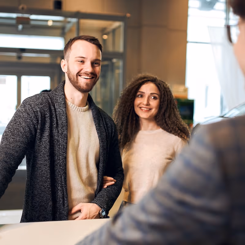 A young couple is checking into a hotel at the reception