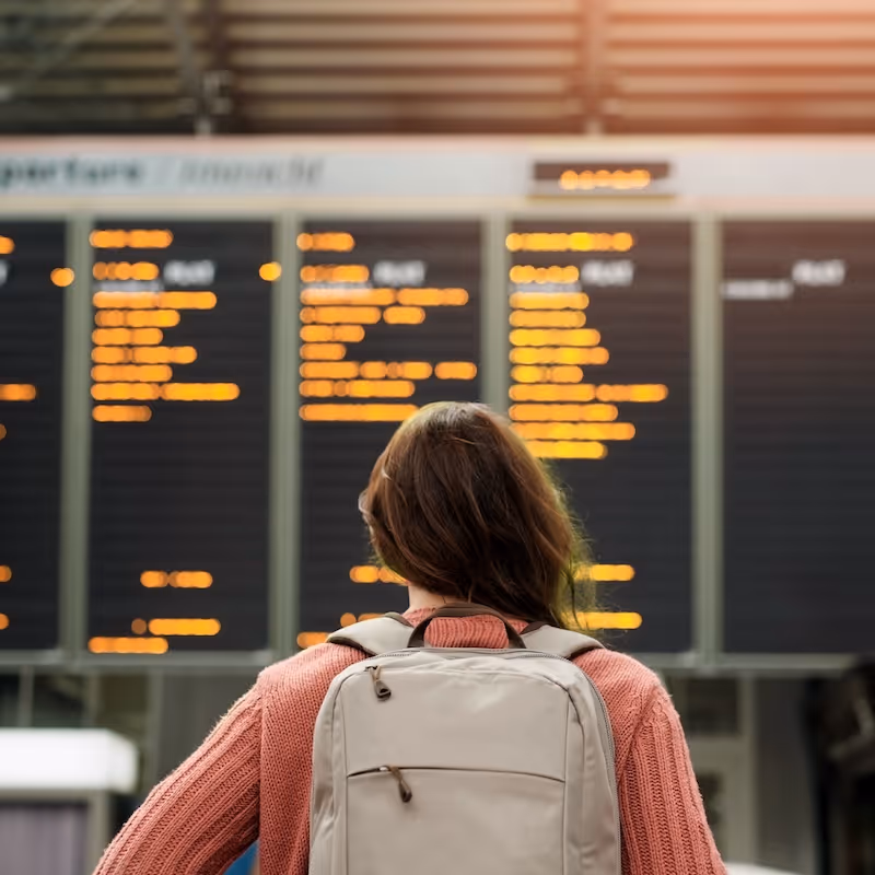 A women stands in front of the display board in an airport