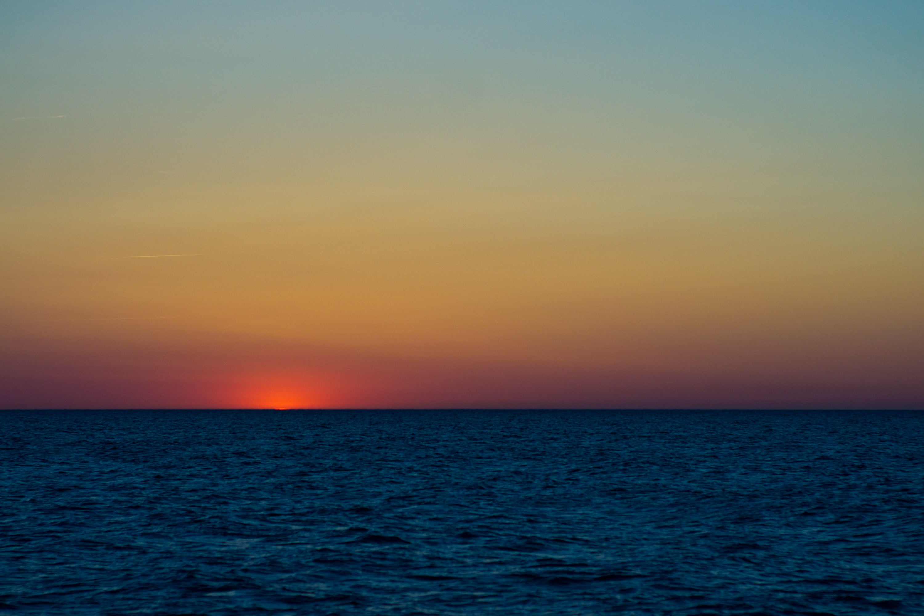 The last of the sun on the horizon of a deep blue sea under a golden sky. Photo: Chris Alfthan