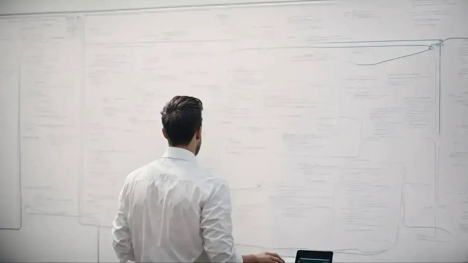 a designer intently sketches the layout of a website on a whiteboard, mapping the user journey with interconnected boxes and annotations.