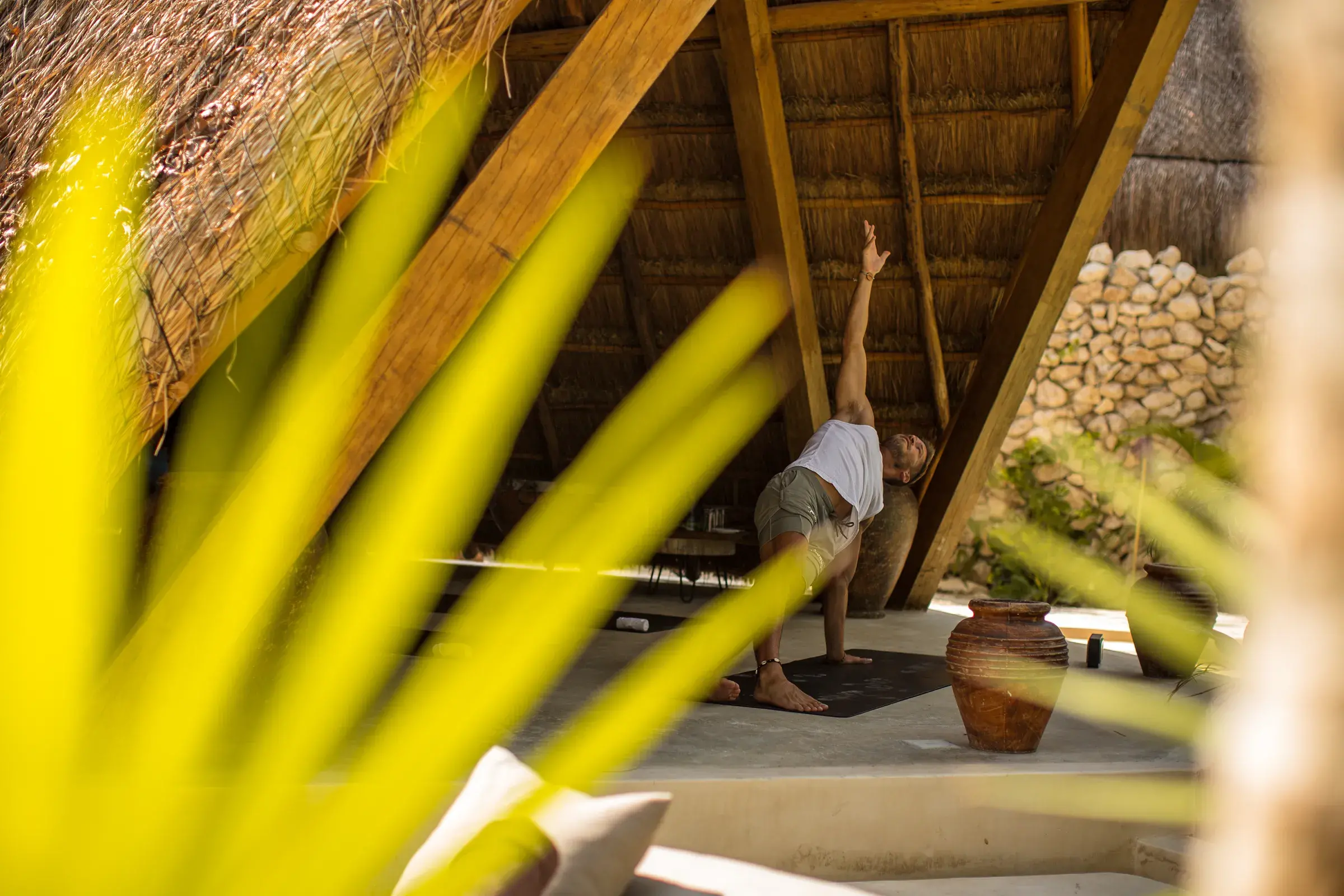 hombre-haciendo-yoga-en-palapa-jarrones