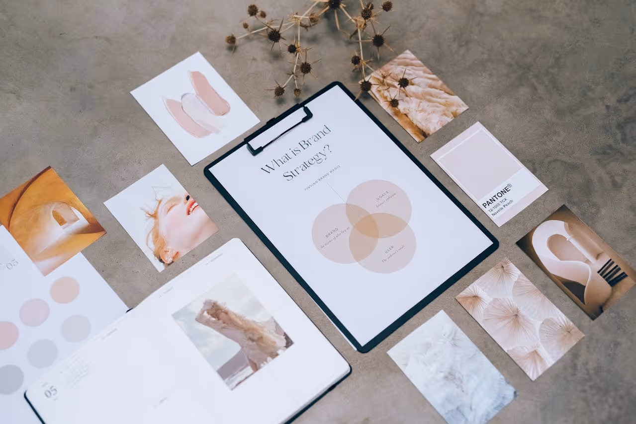 Flat lay of a brand strategy concept with a clipboard paper showing a Venn diagram and various photo prints on a gray surface.