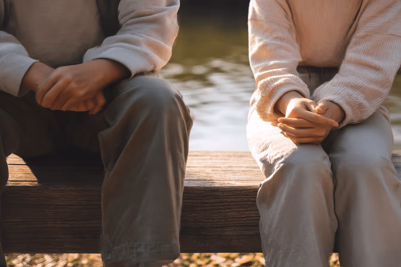 屋外のベンチに横並びで座る男女の足元