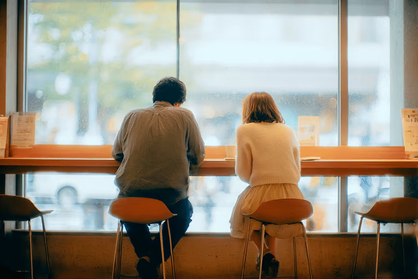 カフェのカウンターに並んで座る男女