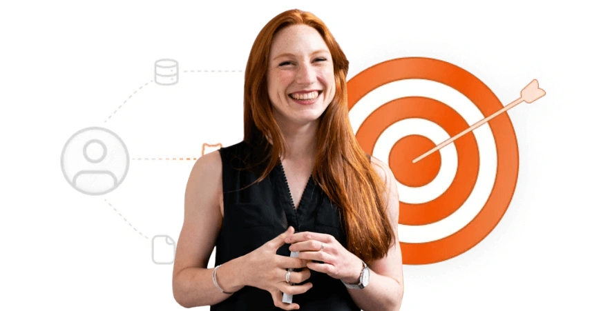 Smiling woman with long red hair standing in front of an orange target with an arrow in the bullseye.