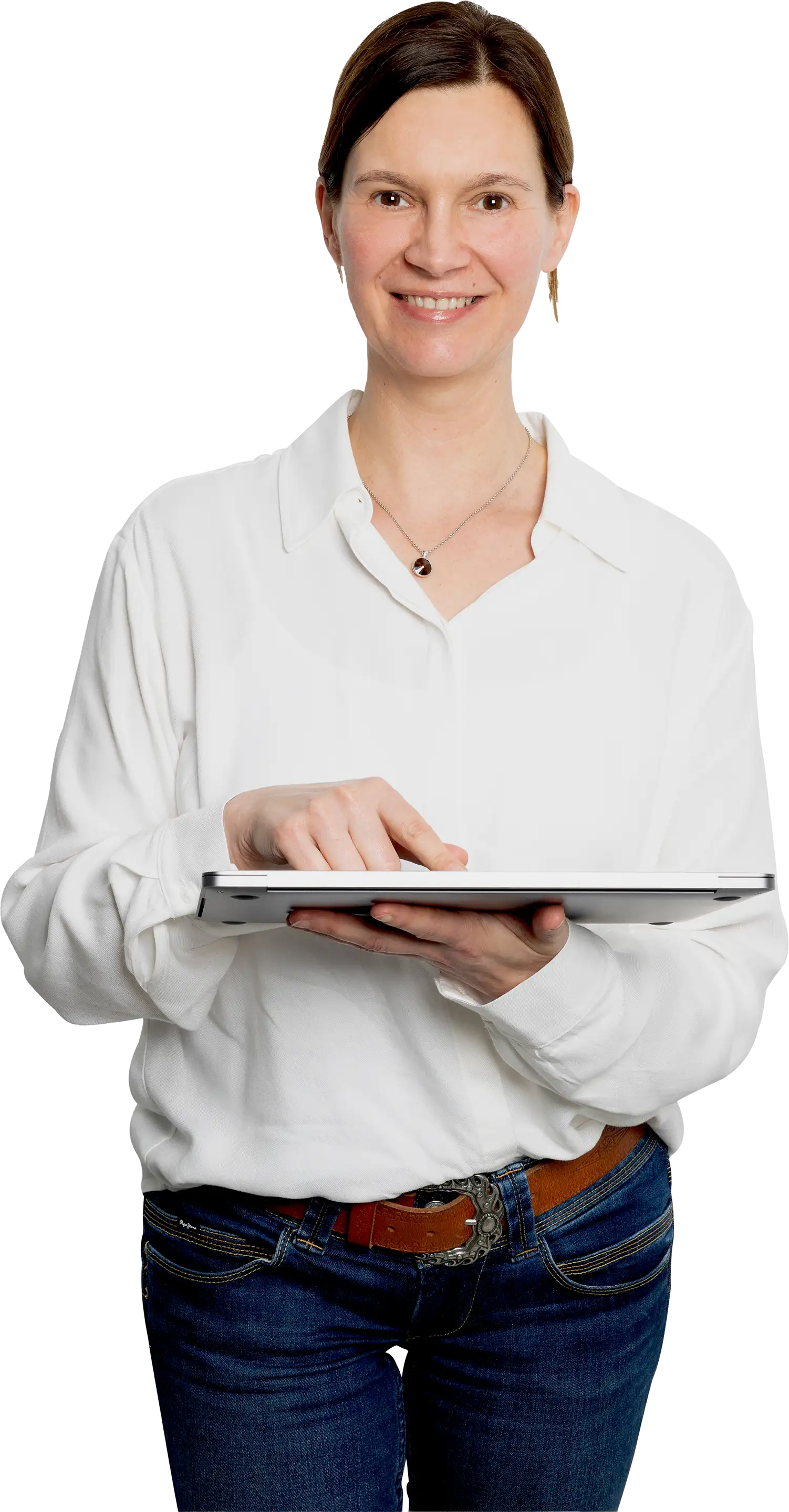 Lächelnde Frau in weißem Hemd und blauer Jeans hält einen Laptop und tippt darauf.